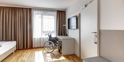 Rollstuhlgerechte Unterkunft - Barrierefreiheit-Merkmale: Für Gäste mit Gehbehinderung oder Rollstuhlfahrer - Donauraum - Schreibtischansicht mit Rollstuhl. Für Begleitpersonen sind teilweise Verbindungstüren zum Nachbarzimmer oder Zustellbetten möglich.  - Hotel Zeitgeist Vienna