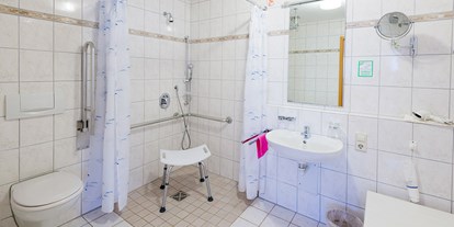Rollstuhlgerechte Unterkunft - Rollstuhlgerechtes Badezimmer mit ebenerdiger Dusche und Duschstuhl - Apartmenthaus Bad Bellingen