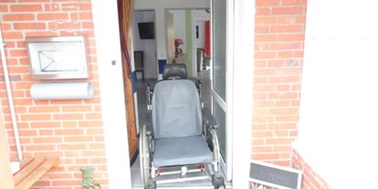Rollstuhlgerechte Unterkunft - Barrierefreiheit-Merkmale: Für Gäste mit Sehbehinderung oder blinde Menschen - Nordseeküste - Beispielfoto mit einem Pflegerollstuhl in der Eingangstür vom Ferienhaus - Ferienhaus Amelsberg