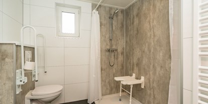 Rollstuhlgerechte Unterkunft - Die Dusche hat einen Sitz und Haltegriffe, einen unterfahrbaren Waschtisch und einen höhenverstellbaren Spiegel. Das Dusch-WC hat klappbare Stützen. Im Flur des Hauses befindet sich noch eine separate Toilette. - Rollstuhl Urlaub in Zeeland - De Klaproos