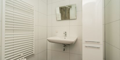 Rollstuhlgerechte Unterkunft - See - Niederlande - Die Dusche hat einen Sitz und Haltegriffe, einen unterfahrbaren Waschtisch und einen höhenverstellbaren Spiegel. Das Dusch-WC hat klappbare Stützen. Im Flur des Hauses befindet sich noch eine separate Toilette. - Rollstuhl Urlaub in Zeeland - De Klaproos