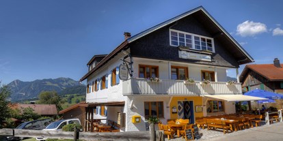 Rollstuhlgerechte Unterkunft - Hauptansicht Berggasthof Sonne mit Biergarten und im Hintergrund der Grünten der "Wächter des Allgäu" - Pflegehotel Allgäu