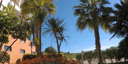 Rollstuhlgerechte Unterkunft - Barrierefreiheit-Merkmale: Für Gäste mit Hörbehinderung oder gehörlose Menschen - Palmen und Blumen vor der Unterkunft - FeWo-Algarve