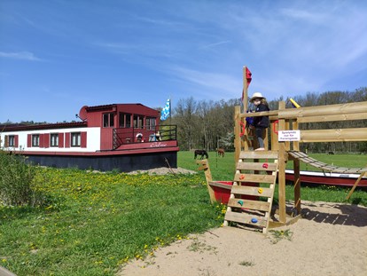 Rollstuhlgerechte Unterkunft - Tauberbischofsheim - Blick von der Terrasse auf das Filmschiff ERBSE und den Spielplatz nur für das Erdhaus und das Filmschiff - Erdhausapartment WEST