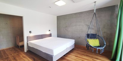 Rollstuhlgerechte Unterkunft - Unterkunftsart: Ferienhaus - Baudenbach - erstes Schlafzimmer mit Doppelbett (1,80m x 2,00m) Boxspringbett und Hängesessel - Erdhausapartment WEST