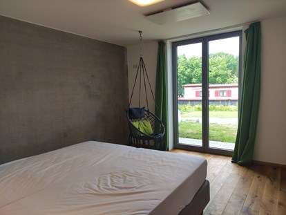 Rollstuhlgerechte Unterkunft - Barrierefreiheit-Merkmale: Für Gäste mit kognitiven Beeinträchtigungen - Tauberbischofsheim -  erstes Schlafzimmer mit Doppelbett und ebenerdiger Ausgang auf die Terrasse - Erdhausapartment WEST