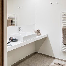 Rollstuhl-Urlaub: Badezimmer mit unterfahrbarem Waschtisch, behindertengerechte Dusche und WC mit Haltegriffen - freiraum Apartments