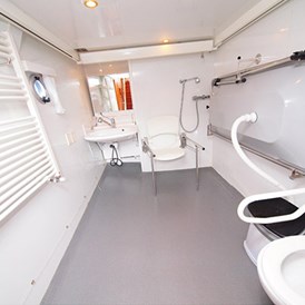 Rollstuhl-Urlaub: Das Bad mit verstellbarem Waschbecken, Dusche, Toilette (beide mit Haltengriffen) und Klappliege. - Behindertengerechtes Motorschiff ARON zum selber fahren