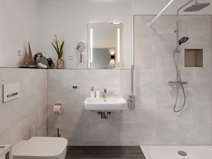Rollstuhlgerechte Unterkunft - Unterkunftsart: Ferienhaus - Badezimmer im Erdgeschoss mit unterfahrbarem Waschbecken inkl. Haltestange, WC inkl Haltestange und ebenerdiger, befahrbarer Dusche (120x120cm) mit Duschstange und Duschhocker - Haus Fichte