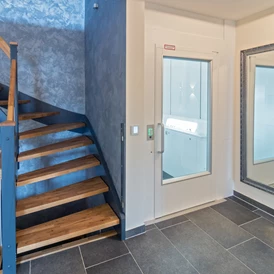 Rollstuhl-Urlaub: Das Treppenhaus mit Aufzug in jedes der drei Stockwerke. - Feriendomizil Nordstern