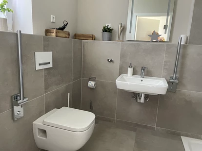 Rollstuhlgerechte Unterkunft - Unterkunftsart: Ferienhaus - WC/Dusche im Erdgeschoss mit unterfahrbarem Waschbecken inkl. Haltegriff und WC inkl Haltegriff - Korn-Koje