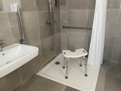 Rollstuhlgerechte Unterkunft - Unterkunftsart: Ferienhaus - Barrierefreie, begehbare Dusche mit Duschhocker und Haltegriff - Korn-Koje