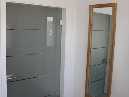 Rollstuhlgerechte Unterkunft - Pflegebett - Eingangsbereich mit Ganzkörperspiegel und Glastür zur Wohnung - Unser Schwalbennest