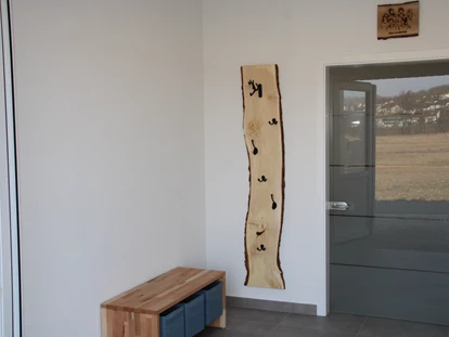 Rollstuhlgerechte Unterkunft - Pflegebett - Eingangsbereich, Bank mit Stauraum und Garderobe aus Holzbrett mit Häken - Unser Schwalbennest