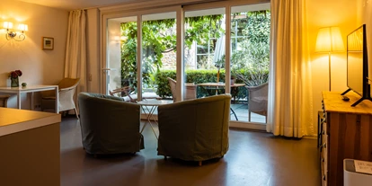 Rollstuhlgerechte Unterkunft - Unterkunftsart: Ferienhaus - Wohn- und Essbereich mit Blick zur Parkanlage - Senhalser Höfe - Apartment Gartenhaus