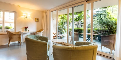 Rollstuhlgerechte Unterkunft - Unterkunftsart: Ferienhaus - Wohn- und Essbereich mit Blick zur Parkanlage - Eingang zum Apartment - Senhalser Höfe - Apartment Gartenhaus