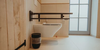 Rollstuhlgerechte Unterkunft - Pflegebett - neben der Toilette ist ausreichend Platz zum Drehen. Die Toilette besitzt Stützklappgriffe - Biohotel Wildland