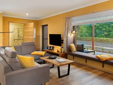 Rollstuhl-Urlaub: Wohnzimmer mit Cougarnitur sowie Panoramafenster.
Im gemütlichen Panoramafenster können  Sie den Blick nach draußen genießen, ein gutes Buch lesen, oder auch schlafen. - Ferienhaus "Milchstraße" im Natur- und Sternenpark Westhavelland