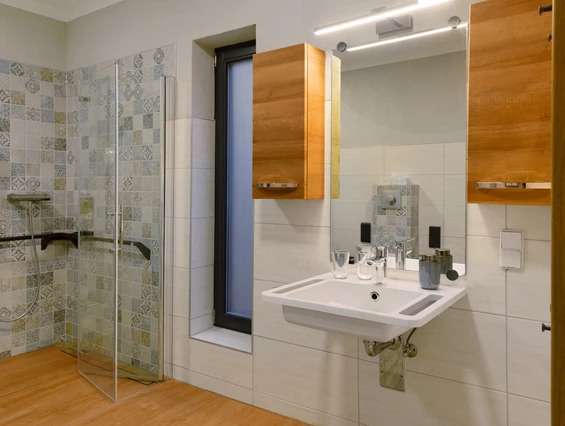 Rollstuhl-Urlaub: Bad mit unterfahrbaren Waschtisch. Optional kann neben den Wandregal und Badschränke, zusätzliche Ablagemöglichkeiten zur Verfügung gestellt werden. - Ferienhaus "Milchstraße" im Natur- und Sternenpark Westhavelland