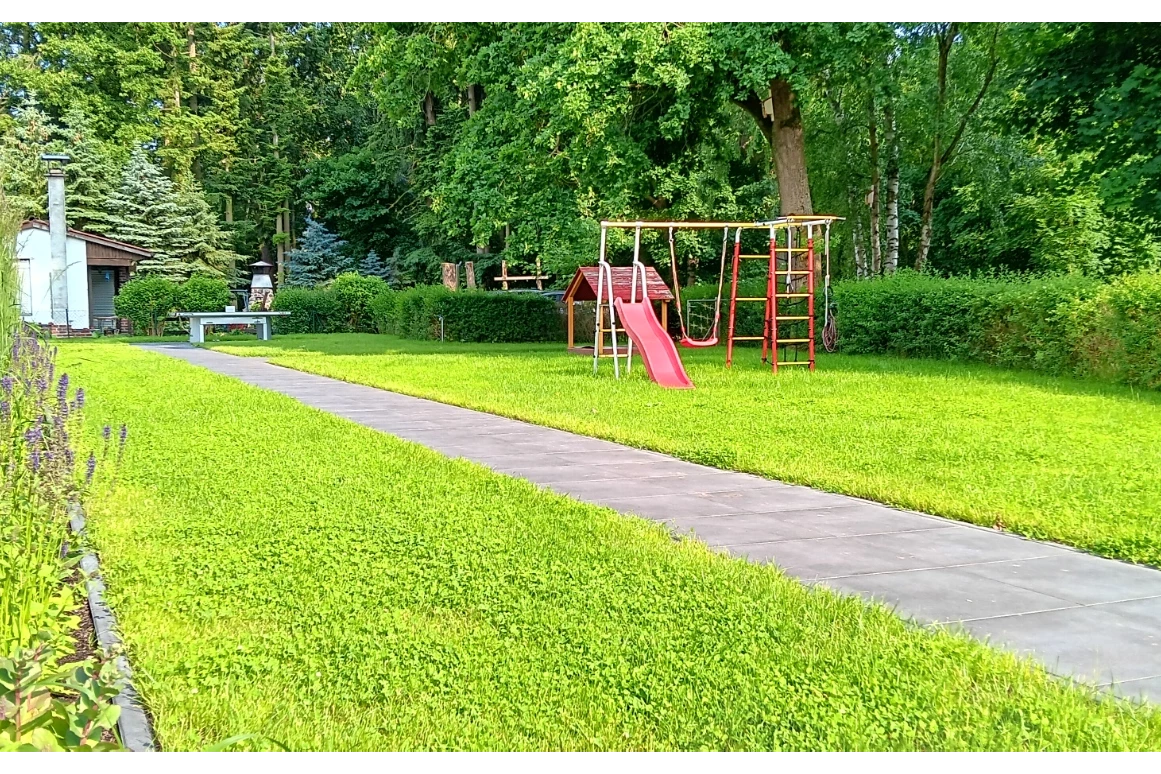Rollstuhl-Urlaub: Ein Kleinkindspielplatz mit Rutsche, Klettergerüst und Schaukel sowie überdachter Sandkasten, warten auf Ihre Kinder. - Ferienhaus "Milchstraße" im Natur- und Sternenpark Westhavelland