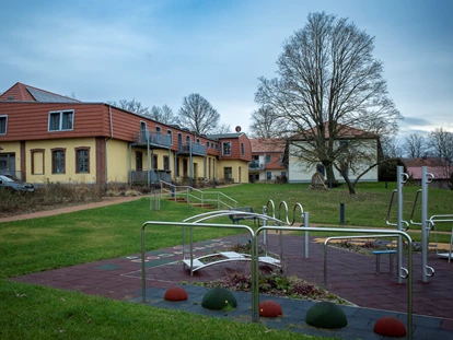 Rollstuhlgerechte Unterkunft - Pflegebett - Spiel und Bewegung im Grünen – Der Park des Gutshofes Roggow
Vor der historischen Kulisse des Gutshofes Roggow erstreckt sich eine weitläufige Rasenfläche, die Kindern und Jugendlichen vielfältige Spiel- und Sportmöglichkeiten bietet. Ein moderner Spielplatz mit Seilbahn, Trampolin, Schaukel und Kleinkinderwippe lädt zum Toben ein, während der Volleyballplatz und der kleine Bolzplatz auch ältere Kinder und Erwachsene zu gemeinsamen Aktivitäten animieren.
Hier finden Feriengäste wie auch Bewohner mit Besuch von Kindern einen idealen Ort, um in sicherer Umgebung frische Luft und Bewegung zu genießen – eingebettet in die gepflegte Parklandschaft des Gutshofes. - Gutshof Roggow bei Güstrow