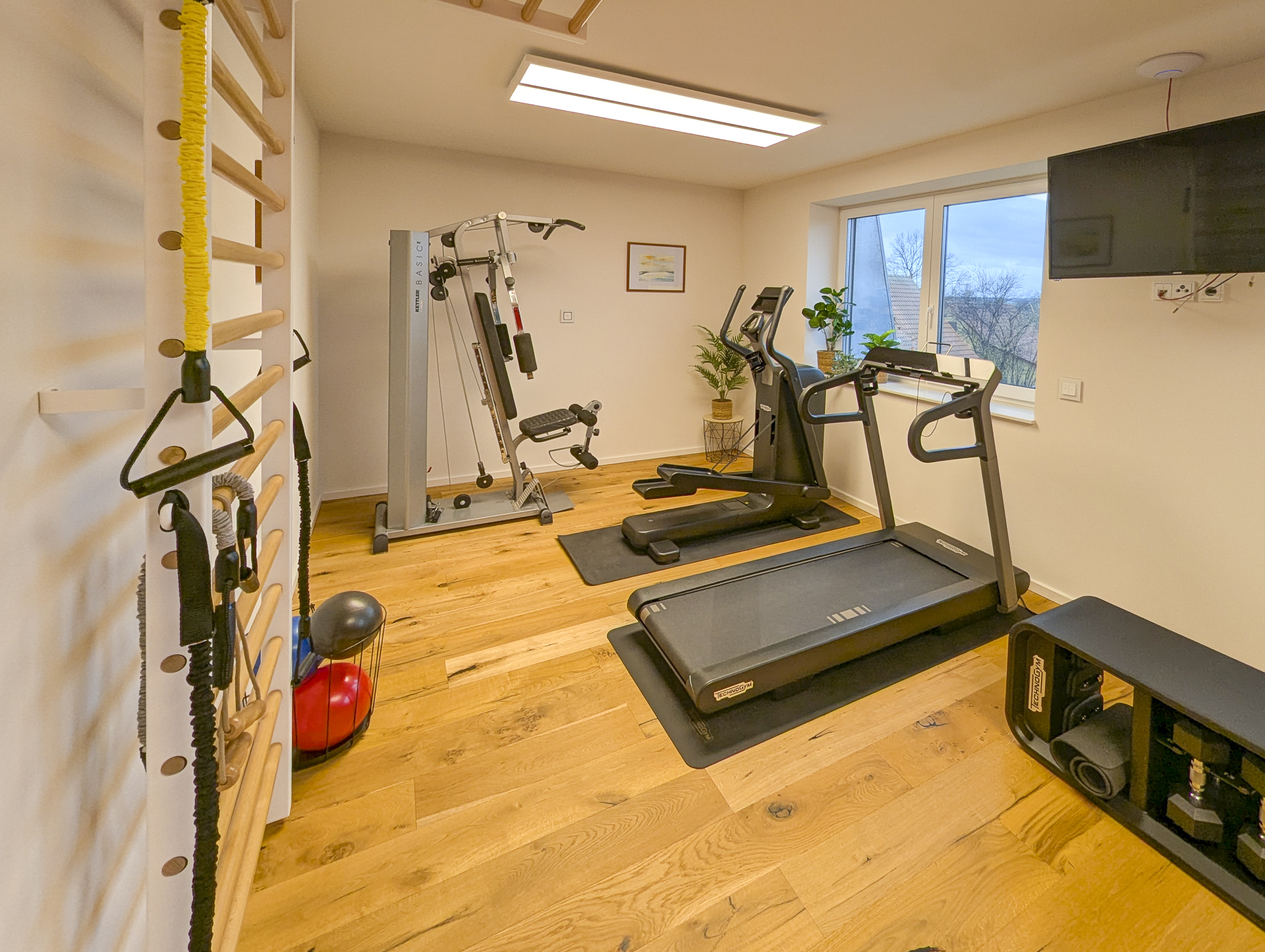 Rollstuhl-Urlaub: Aktiv bleiben – Das Fitnesscenter im Gutshof Roggow

Das hauseigene Fitnesscenter steht allen Gästen und Bewohnern kostenfrei zur Verfügung und bietet hochwertige Geräte für ein umfassendes Training: Crosstrainer, Bike und Kraftstation von Technogym, die bewährte Rudermaschine von Concept2 sowie Sprossenwand und Freihanteln. Abgerundet wird das Angebot durch einen Massagesessel – ideal zur Entspannung nach dem Training. Große Fenster sorgen für einen hellen, freundlichen Raum mit Blick ins Grüne. - Gutshof Roggow bei Güstrow