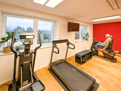 Rollstuhlgerechte Unterkunft - Pflegebett - Aktiv bleiben – Das Fitnesscenter im Gutshof Roggow
Das hauseigene Fitnesscenter steht allen Gästen und Bewohnern kostenfrei zur Verfügung und bietet hochwertige Geräte für ein umfassendes Training: Crosstrainer, Bike und Kraftstation von Technogym, die bewährte Rudermaschine von Concept2 sowie Sprossenwand und Freihanteln. Abgerundet wird das Angebot durch einen Massagesessel – ideal zur Entspannung nach dem Training. Große Fenster sorgen für einen hellen, freundlichen Raum mit Blick ins Grüne. - Gutshof Roggow bei Güstrow