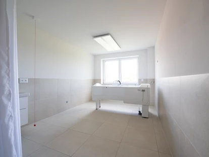Rollstuhlgerechte Unterkunft - Pflegebett - Komfort ohne Barrieren – Rollstuhlgerechte Bäder im Gutshof Roggow
Neben den barrierefreien Bädern in den Gästezimmern verfügen beide Häuser des Gutshofes über großzügige, nach höchsten Standards eingerichtete rollstuhlgerechte Bäder. Sie sind mit bodengleichen Duschen, Haltegriffen, unterfahrbaren Waschbecken sowie modernster Ausstattung versehen und bieten damit optimale Bedingungen für Gäste mit besonderen Mobilitätsbedürfnissen. - Gutshof Roggow bei Güstrow