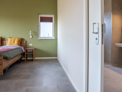Rollstuhlgerechte Unterkunft - Unterkunftsart: Ferienhaus - Schlafzimmer mit Schiebetür zum Badezimmer - Landgoed Oud Bommenede