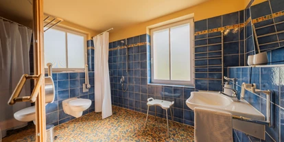 Rollstuhlgerechte Unterkunft - Unterkunftsart: Ferienhaus - Badezimmer mit befahrbarer Dusche im Erdgeschoss (zus. Sauna, nicht befahrbar) - Reetdachhaus mit Schwimmteich in Krienke