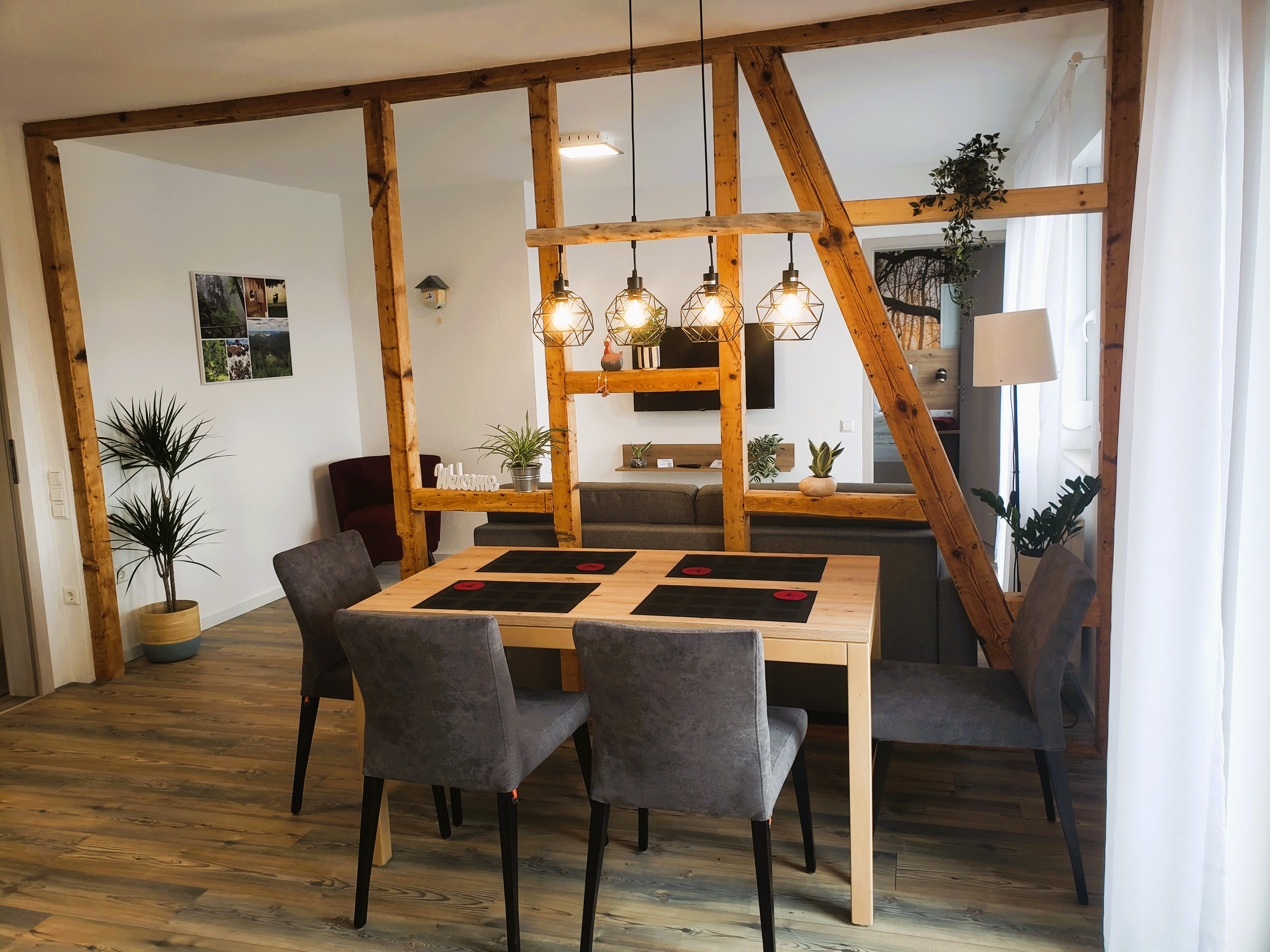 Rollstuhlgerechte Unterkunft - Barrierefreiheit-Merkmale: Für Gäste mit Gehbehinderung oder Rollstuhlfahrer - Schwarzwald - Moderner Essbereich mit Holztisch und gepolsterten Stühlen. Offene Holzbalken und stilvolle Hängeleuchten schaffen eine warme und gemütliche Atmosphäre im Wohnraum. - Pension Alter Hirsch - Ferienwohnung Tanne