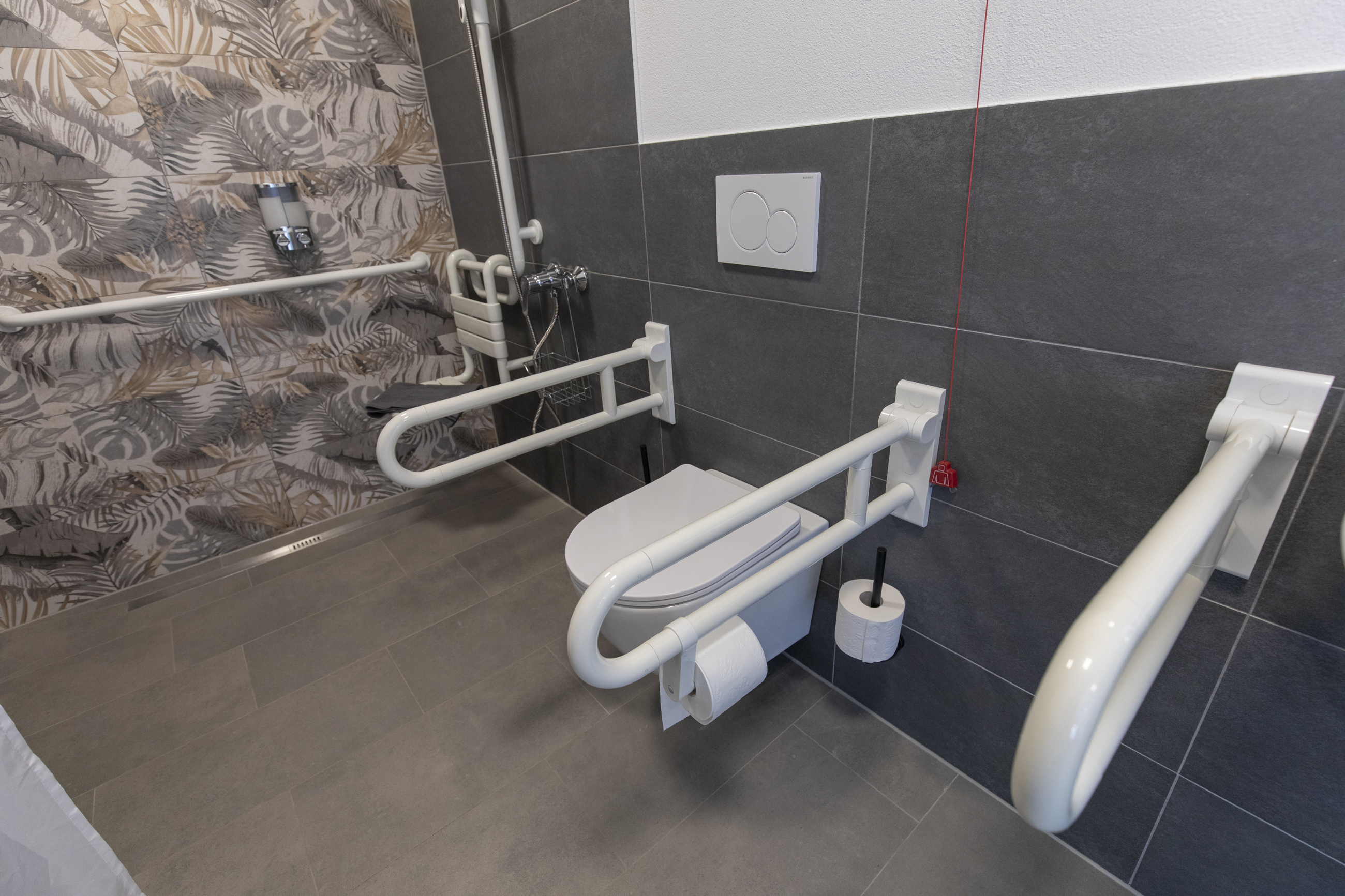 Rollstuhl-Urlaub: Detailaufnahme des barrierefreien Badezimmers mit Toilette und stabilen Haltegriffen. Die moderne Gestaltung sorgt für Sicherheit und Komfort. - Pension Alter Hirsch - Ferienwohnung Tanne