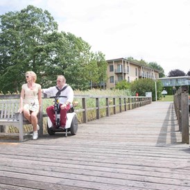 Rollstuhl-Urlaub: mit dem Rollstuhl befahrbarer Holzsteg - Seehotel Rheinsberg - komplett barrierefreies Hotel am See