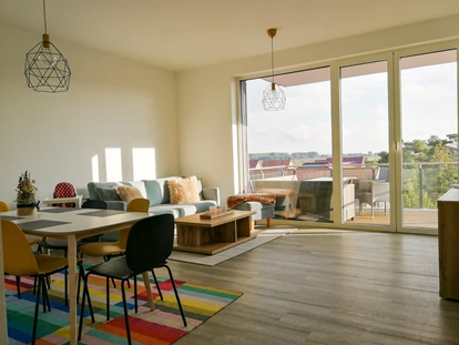 Rollstuhlgerechte Unterkunft - Wohn- und Essbereich mit barrierefreiem Zugang zum Balkon. Die Balkontür lässt sich komplett öffnen, sodass genügen Platz entsteht. - MeerOstseeZeit