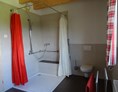 Rollstuhl-Urlaub: Großzügige Dusche und WC im Tageslichtbad, Duschhocker und unterfahrbares Waschbecken vorhanden - Mooshof