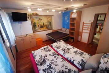 Rollstuhl-Urlaub: Schlafzimmer mit normalem Doppelbett.
Das zweite Bett beim Bild ist eine elektrische Therapieliege mit 120x180 cm. - Ferienwohnung Kaiserblick Kössen