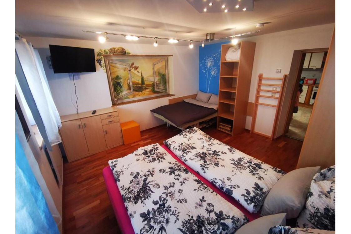 Rollstuhl-Urlaub: Schlafzimmer mit normalem Doppelbett.
Das zweite Bett beim Bild ist eine elektrische Therapieliege mit 120x180 cm. - Ferienwohnung Kaiserblick Kössen