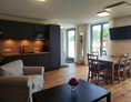 Rollstuhl-Urlaub: offene Küche und Wohnzimmer mit direktem ebenerdigen Zugang auf die Terrasse - Erdhausapartment OST