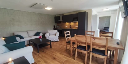 Rollstuhlgerechte Unterkunft - Unterkunftsart: Ferienhaus - Wohnzimmer mit 3-SitzerSofa, 2-SitzerSofa und Sessel - Erdhausapartment OST