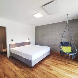 Rollstuhl-Urlaub: erstes Schlafzimmer mit Doppelbett (1,80m x 2,00m) Boxspringbett und Hängesessel - Erdhausapartment WEST