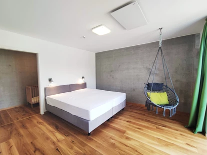 Rollstuhlgerechte Unterkunft - Unterkunftsart: Ferienhaus - erstes Schlafzimmer mit Doppelbett (1,80m x 2,00m) Boxspringbett und Hängesessel - Erdhausapartment WEST