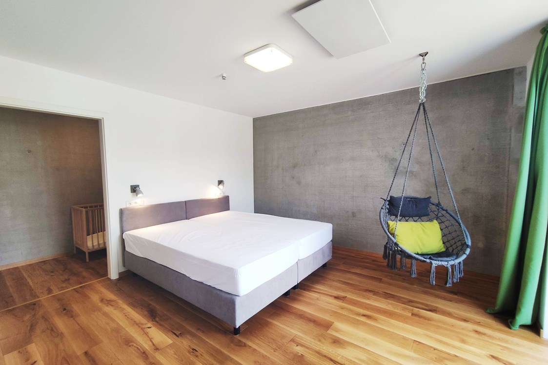 Rollstuhl-Urlaub: erstes Schlafzimmer mit Doppelbett (1,80m x 2,00m) Boxspringbett und Hängesessel - Erdhausapartment WEST
