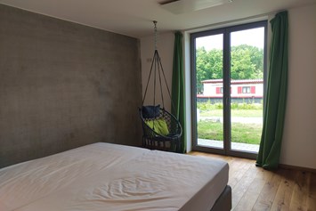 Rollstuhl-Urlaub:  erstes Schlafzimmer mit Doppelbett und ebenerdiger Ausgang auf die Terrasse - Erdhausapartment WEST