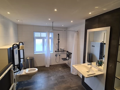 Rollstuhlgerechte Unterkunft - Unterkunftsart: Ferienhaus - Haus 1 - Großes Duschbad mit elektrisch höhenverstellbaren WC und Waschbecken - Stiftung Friedrich Wilhelm und Monika Kertz