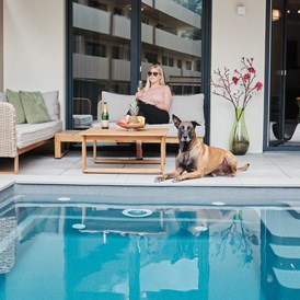 Rollstuhl-Urlaub: Das Bild ist aus unserer Poolsuite Ferdinand - P01.
Nur dieses Apartment hat einen Pool.
Auf dem Foto sitzt eine Frau mit Ihrem Hund auf der Terrasse vor dem Pool. - Kaiserapartments - Wohnpark Graz Gösting